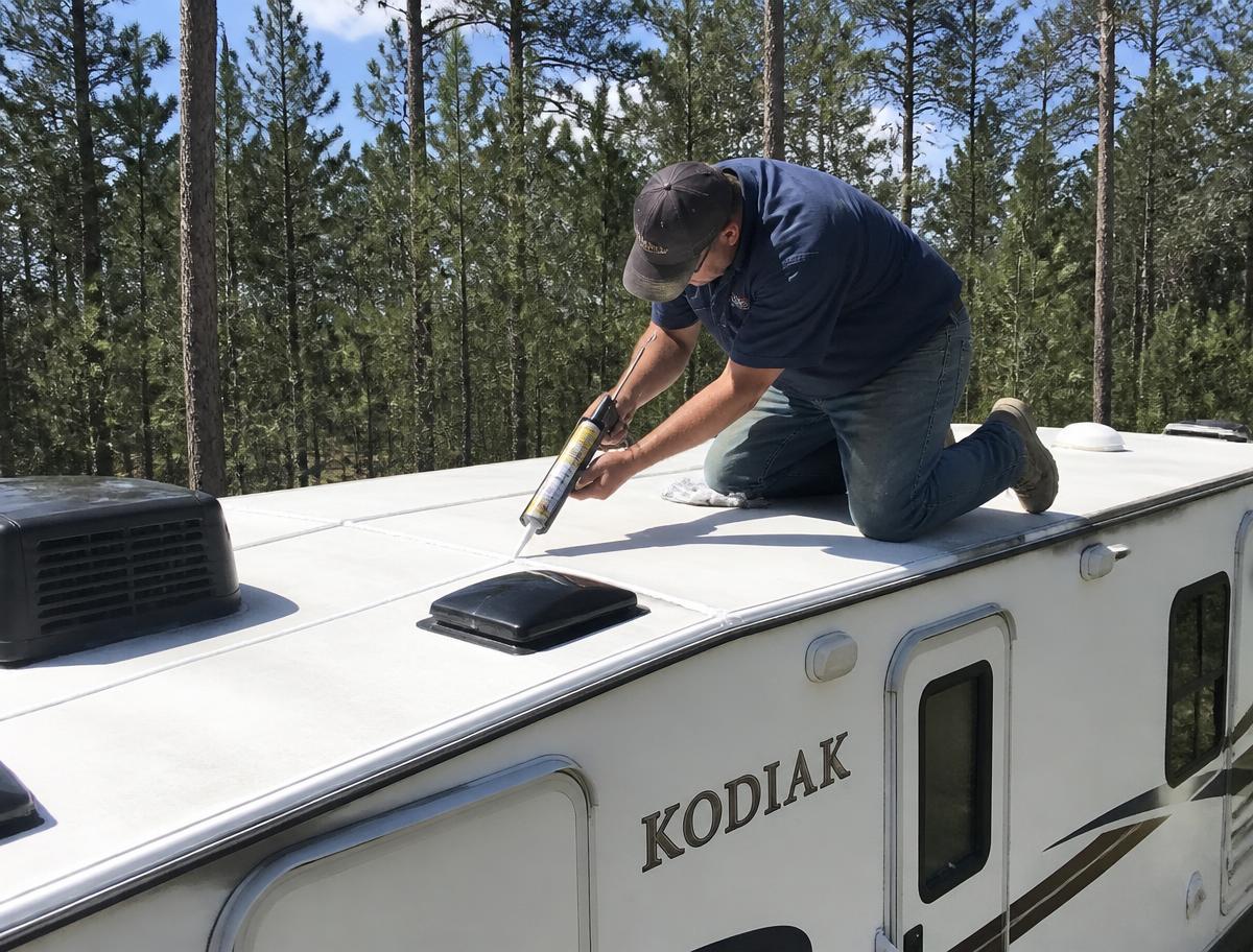 Mobile RV technician resealing roof seams on a travel trailer near Conroe, Texas